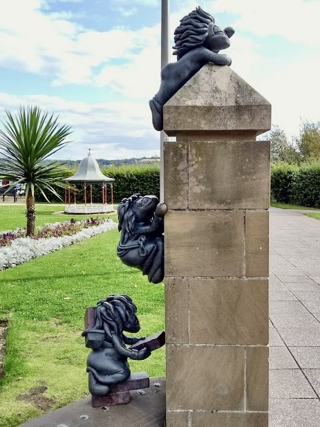 The Lemmings statues in Seabraes, Dundee: three bronze lemmings on a sandstone pillar, one perched on top, one climbing the side and a builder laying bricks at the bottom
